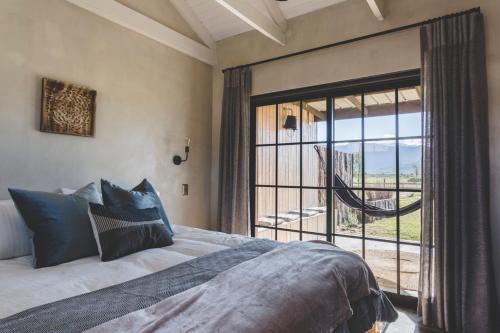 a bedroom with a bed and a large window at The Farmstead in Franschhoek