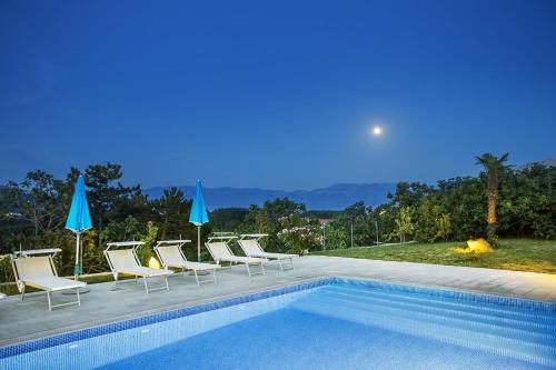 a swimming pool with lounge chairs and umbrellas next to at Apartments Juranic I in Baška