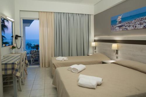 a hotel room with two beds and a balcony at Irene Studios in Mastichari