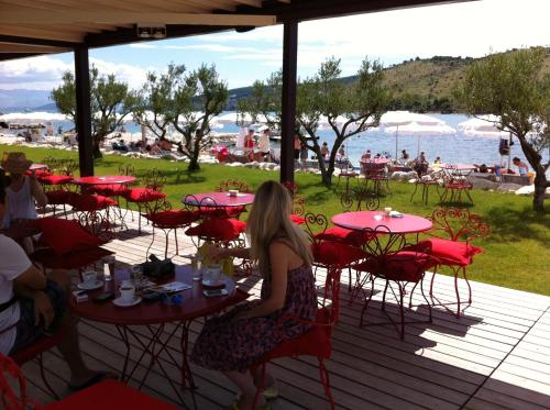 a woman sitting at tables on a deck near the water at Apartments Svilan in Trogir