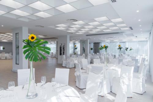 a banquet hall with white tables and chairs and a sunflower at Hotel Villa Maria in Crispiano