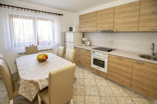 cocina con mesa y sillas y cocina con fregadero en Apartments Juranić en Baška