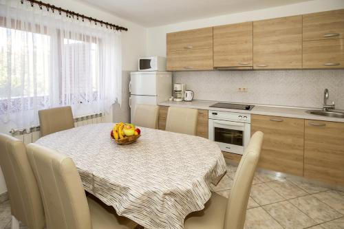 a kitchen with a table with a bowl of fruit on it at Apartments Juranić in Baška