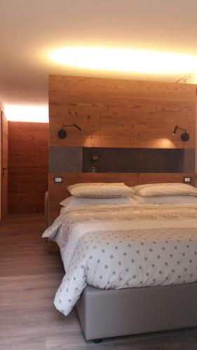 a bedroom with a large bed with a wooden headboard at B&B Al Castel in Padola