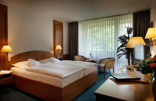 a hotel room with a large bed and a desk at Hotel Fontana in Bad Kissingen