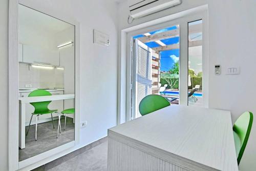 a kitchen with green chairs and a table with a view at Apartmani Elio in Umag