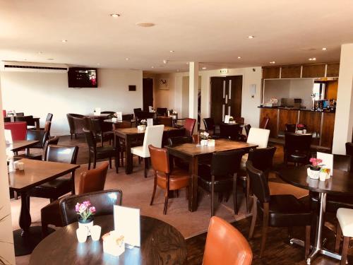 un restaurant avec des tables, des chaises et des tables en bois dans l'établissement Stoneleigh Park Lodge, à Leamington Spa