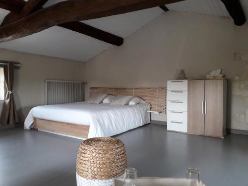een slaapkamer met een wit bed en een houten kast bij Le Marais Picotin in Saint-Pierre-le-Vieux