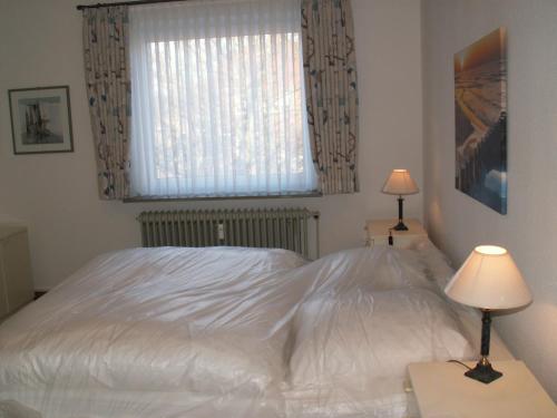 1 cama blanca en un dormitorio con ventana en Sylt, en Leck