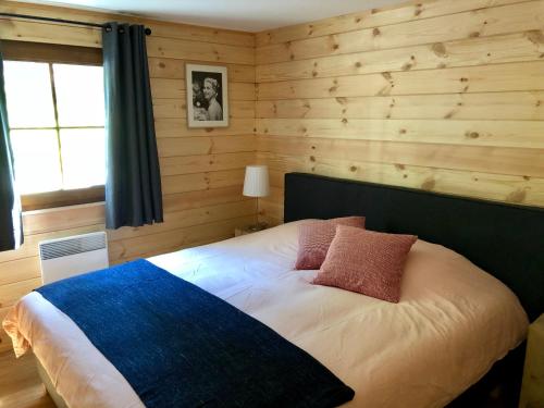 a bedroom with a bed in a room with wooden walls at Chalet de charme, le "Caribou Lodge", Eifel belge in Bullange