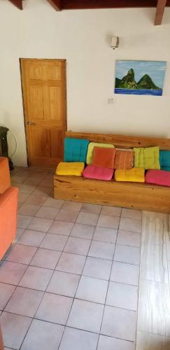 a room with a long wooden couch with colorful pillows at A Private Room in Paradise, Vieux Fort in Vieux Fort