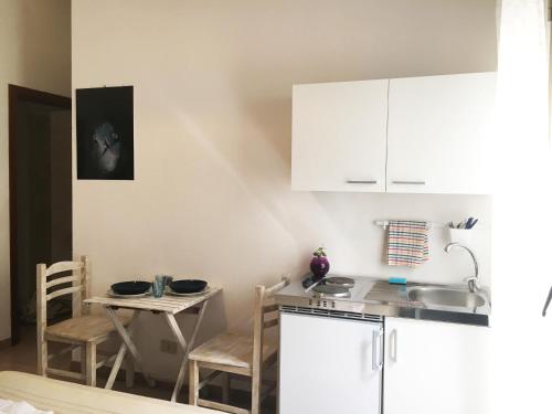 a kitchen with white cabinets and a small table at Blu Rooms Marettimo in Marettimo