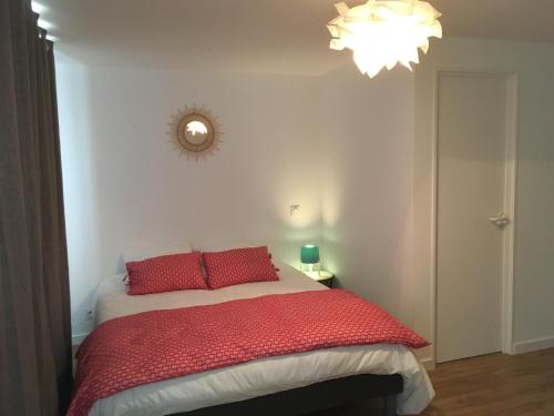コンカルノーにあるCoeur de ville ideal place confortable cosy terrasse hyper centreのベッドルーム1室(赤い枕とシャンデリア付きのベッド1台付)