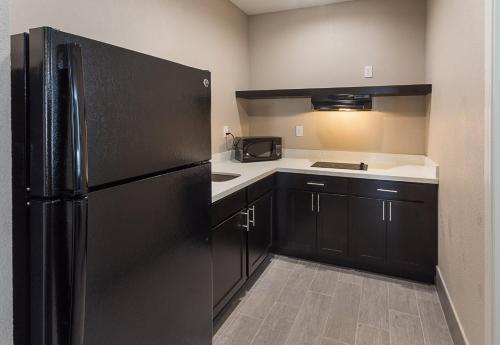 a kitchen with a black refrigerator and black cabinets at Econo Lodge Inn & Suites Houston NW-Cy-Fair in Houston