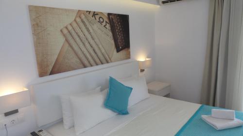 ein weißes Schlafzimmer mit einem blauen Kissen auf einem Bett in der Unterkunft Cosmopolitan Hotel in Kos-Stadt