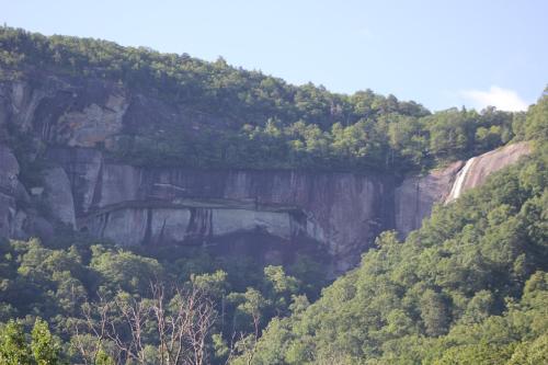 a rocky mountain with trees on top of it at The Evening Shade River Lodge and Cabins in Chimney Rock