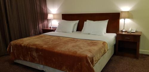 a hotel room with a large bed with two night stands at Top Hotel Apartments in Al Ain