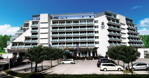 a large white building with cars parked in a parking lot at Grand Hotel Donat Superior & Wellness Center in Rogaška Slatina