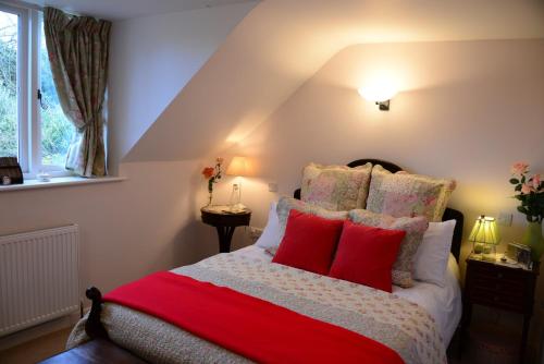 a bedroom with a bed with red pillows at Middle Farm Cottage in Wells