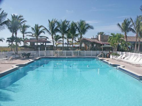 a large swimming pool with palm trees in the background at The Beachcomber St. Pete Beach Resort & Hotel in St. Pete Beach