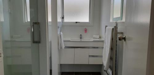 a white bathroom with a sink and a mirror at Rose Apartments Unit 3 Central Rotorua - Accommodation & Spa in Rotorua