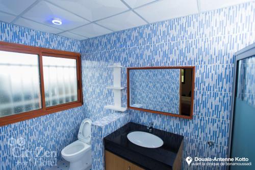 a blue tiled bathroom with a sink and a mirror at Cityzen Hotel in Douala