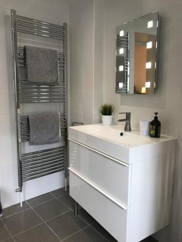 La salle de bains est pourvue d'un lavabo blanc et d'un miroir. dans l'établissement The Harbour Studio, à Portrush