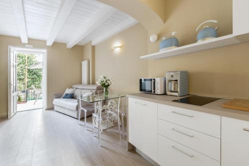a kitchen with white cabinets and a glass table at Residenza La Zagara in Cannero Riviera