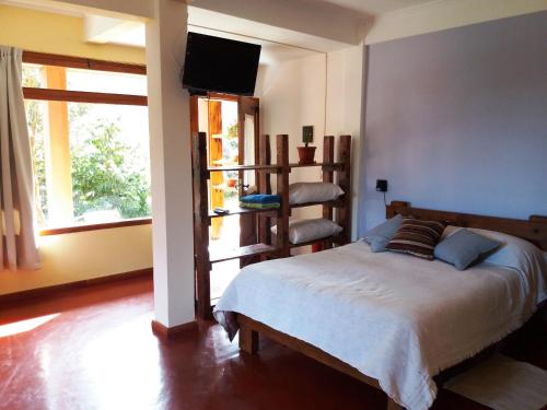 a bedroom with a bed and a tv and a window at El Portal del Lago in Lago Puelo