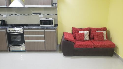 a kitchen with a couch with red cushions and a microwave at Complejo EL ANGEL in Río Colorado