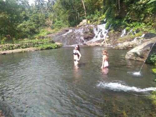 two girls in the water near a waterfall at Sugi Gede Homestay in Singaraja