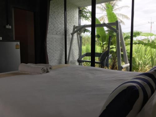 a bed in a room with a large window at Coco Coozy in Kanchanaburi