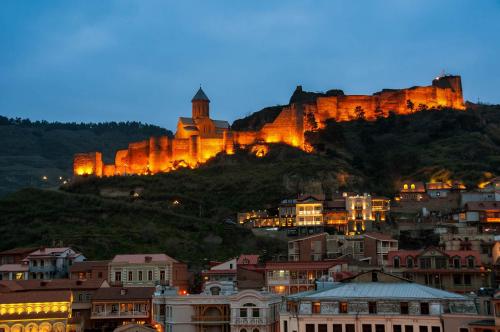 a city with a castle on a hill at night at Boutique Hotel Mimino in Tbilisi City