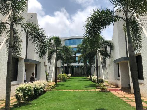 a building with palm trees in front of it at Pai Resort in Belgaum