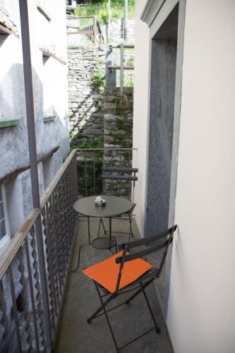 a small table and a chair on a balcony at Palazzo Gamboni Swiss Historic Hotel in Comologno