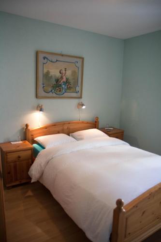 a bedroom with a large white bed and a painting on the wall at Palazzo Gamboni Swiss Historic Hotel in Comologno