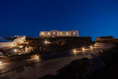 a building on a hill with lights at night at Cape Mykonos in Mýkonos City