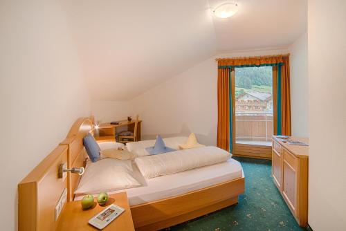 een slaapkamer met een bed, een bureau en een raam bij Appartement Bergkristall in San Giovanni in Val Aurina