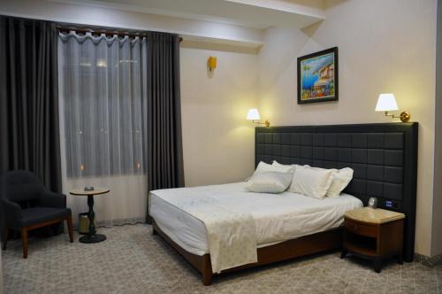 a bedroom with a bed and a chair and a window at Parliament Palace Hotel in Khujand