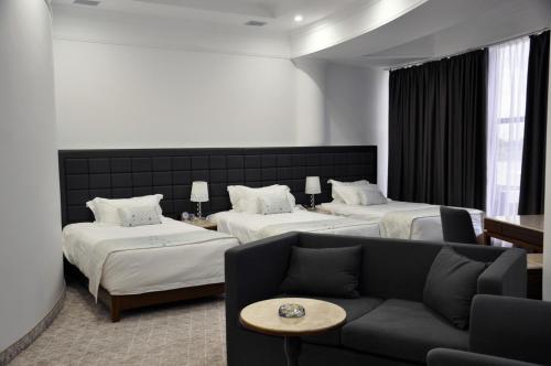 a hotel room with two beds and a couch at Parliament Palace Hotel in Khujand