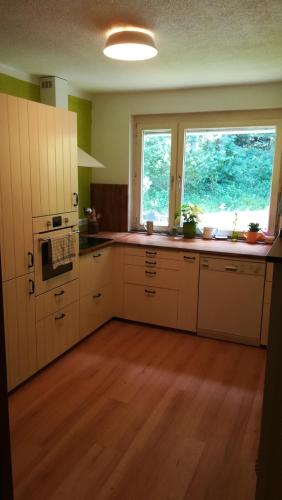 a kitchen with white cabinets and a large window at Ferienhaus am Waldrand in Ampflwang im Hausruckwald