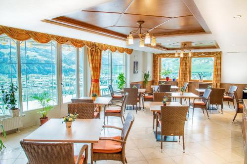 un restaurante con mesas, sillas y ventanas en Hotel Sonnenheim, en Vipiteno