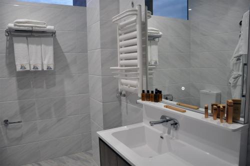 a white bathroom with a sink and a mirror at Parliament Palace Hotel in Khujand