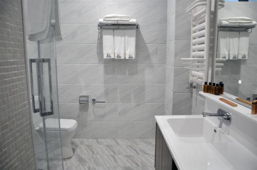 a white bathroom with a toilet and a sink at Parliament Palace Hotel in Khujand