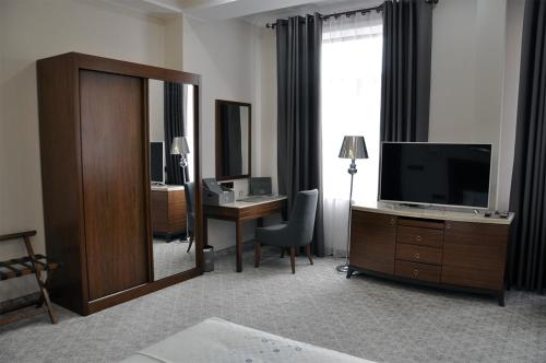 a hotel room with a television and a desk with a mirror at Parliament Palace Hotel in Khujand