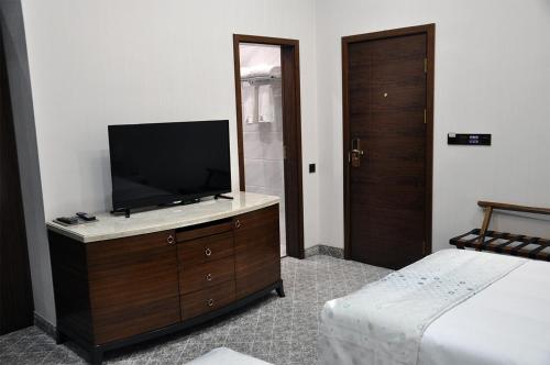 a bedroom with a television on a dresser with a bed at Parliament Palace Hotel in Khujand