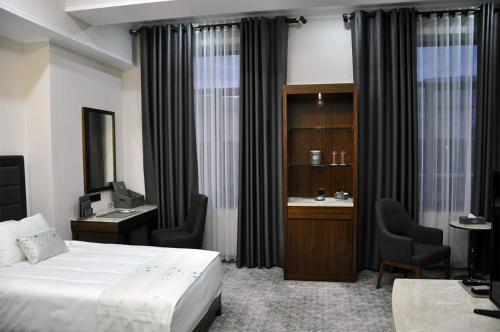 a hotel room with a bed and a desk and chair at Parliament Palace Hotel in Khujand