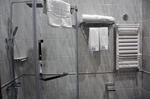a shower with a glass door and towels at Parliament Palace Hotel in Khujand