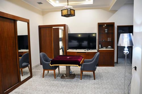 a living room with a table and chairs and a television at Parliament Palace Hotel in Khujand