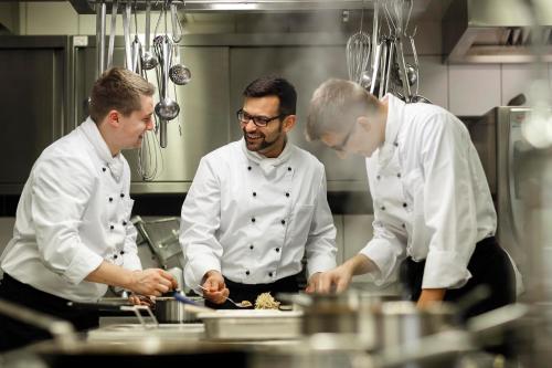 three chefs standing in a kitchen preparing food at Gasthaus Hummel in Duggendorf